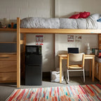 A dorm room with a bed loft, combination unit, and desk setup in a grey and pink color palette
