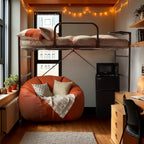 A dorm room with a bed loft, bean bag, combination unit, and desk setup in an orange color palette
