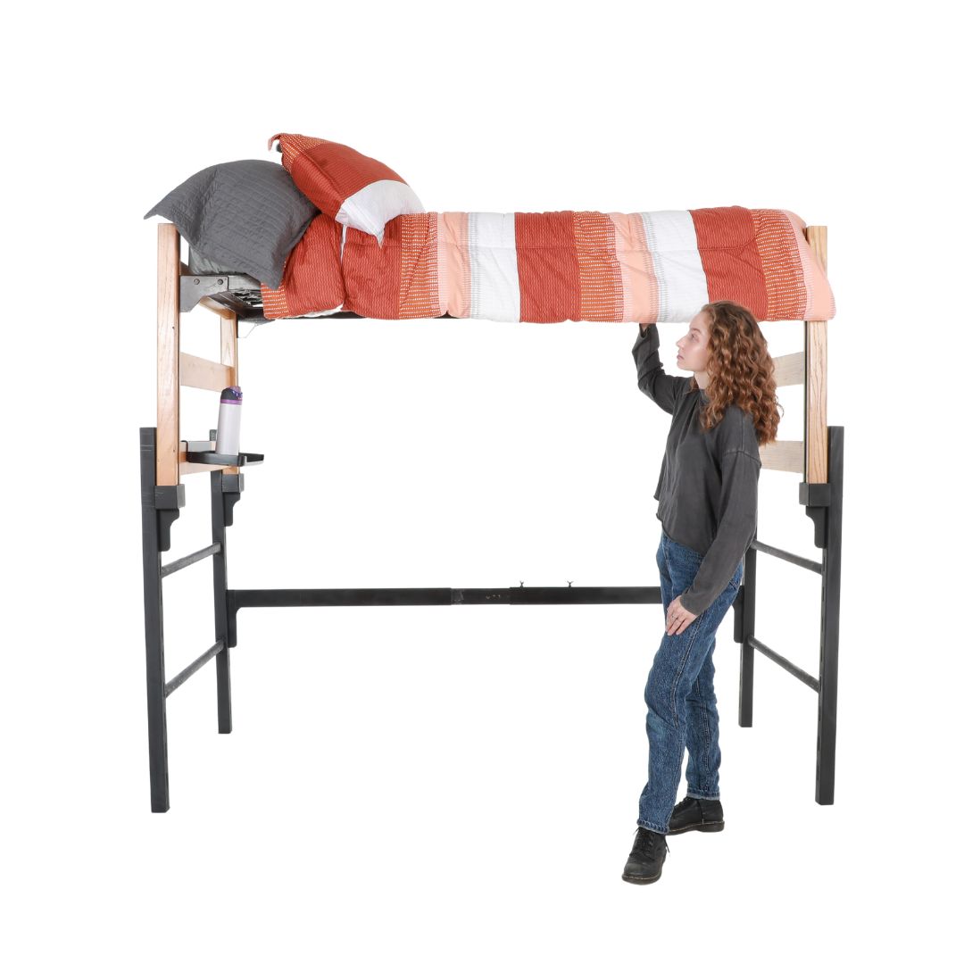 A wooden and metal loft with a pop-out shelf and orange and white comforter being made by an actor