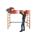 A wooden bed loft with an orange and white comforter being made by an actor