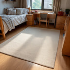 A dorm room setup with wooden furniture and a large rug in a beige color palette