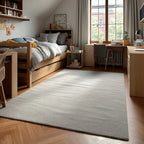 A dorm room setup with a bed loft, desks, and chairs in a grey color palette