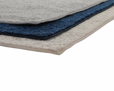 A grey, navy, and beige rug stacked through a view of the rug corners